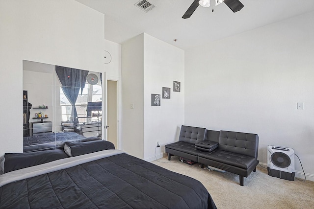 bedroom featuring a high ceiling, light carpet, and ceiling fan