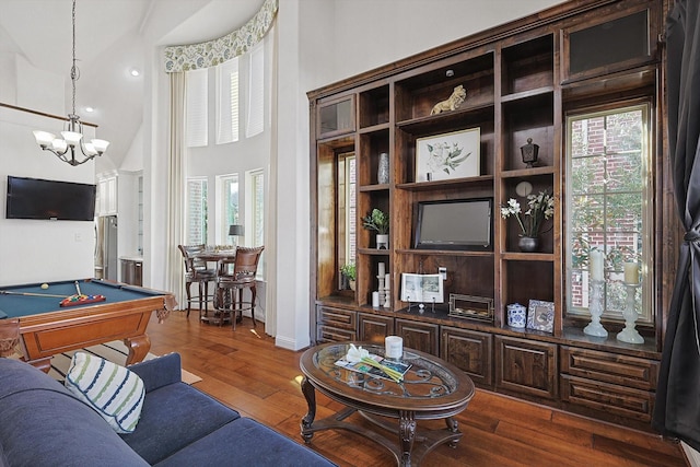 living room featuring a high ceiling, dark hardwood / wood-style flooring, billiards, and an inviting chandelier