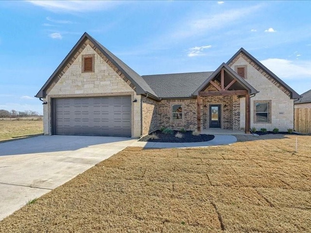 view of front of house featuring stone siding, driveway, an attached garage, and a front lawn