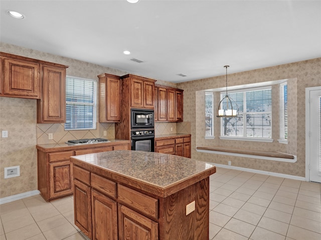 kitchen featuring black appliances, plenty of natural light, a kitchen island, and a chandelier