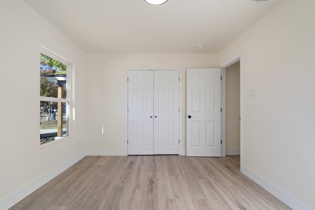 unfurnished bedroom with multiple windows, a closet, and light hardwood / wood-style flooring