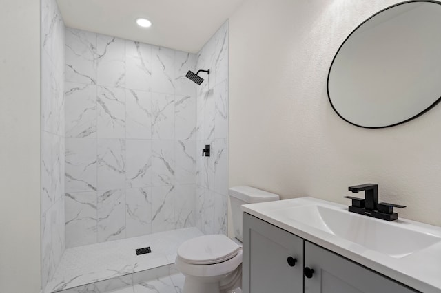 bathroom with tiled shower, vanity, and toilet