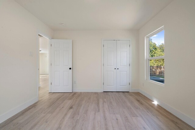 unfurnished bedroom with light wood-type flooring and a closet