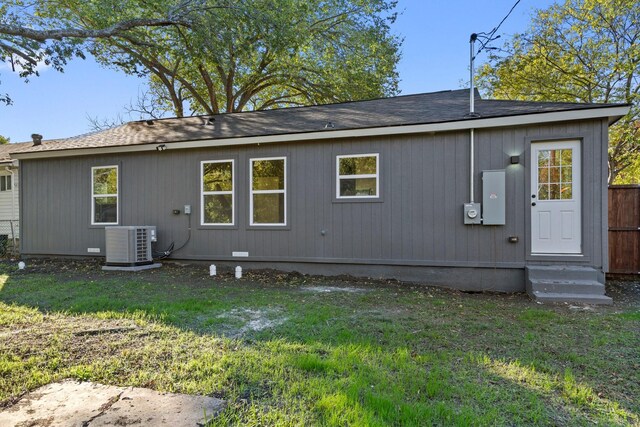 rear view of property featuring cooling unit and a lawn