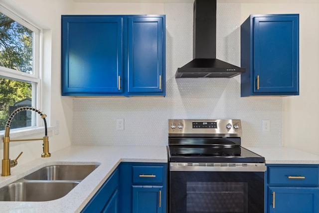 kitchen featuring blue cabinetry, wall chimney exhaust hood, sink, and stainless steel range with electric cooktop