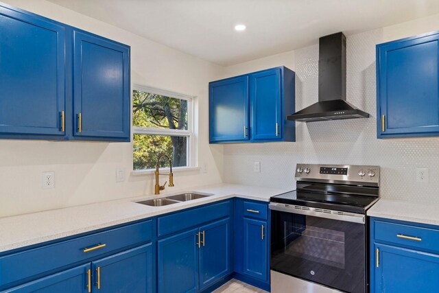 kitchen with wall chimney exhaust hood, sink, blue cabinets, and stainless steel electric range oven