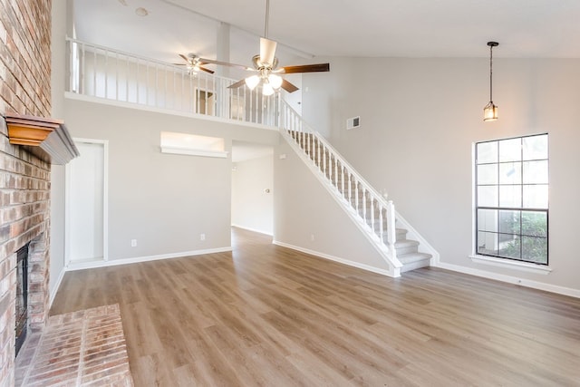 unfurnished living room featuring a fireplace, light wood-type flooring, high vaulted ceiling, and ceiling fan