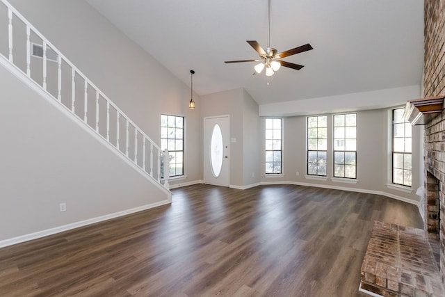 foyer featuring ceiling fan, a healthy amount of sunlight, dark wood-type flooring, and a brick fireplace