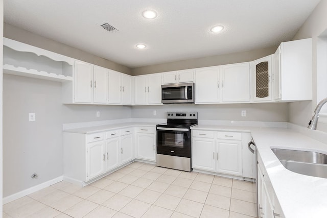 kitchen with sink, white cabinets, light tile patterned floors, and appliances with stainless steel finishes