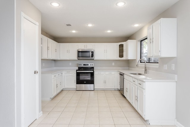 kitchen featuring sink, white cabinets, light tile patterned floors, and appliances with stainless steel finishes