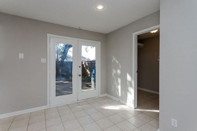 tiled empty room with french doors and a textured ceiling