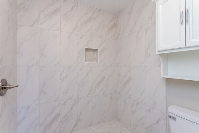 bathroom with toilet and tiled shower