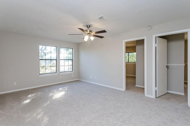 unfurnished bedroom with a textured ceiling, light colored carpet, and ceiling fan