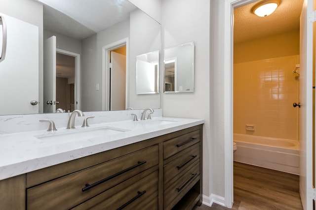 full bathroom featuring vanity, a textured ceiling, bathing tub / shower combination, hardwood / wood-style floors, and toilet