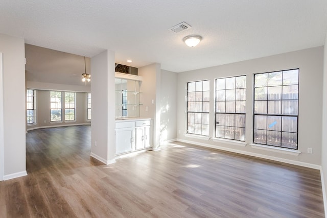 unfurnished living room with ceiling fan, a textured ceiling, and hardwood / wood-style flooring