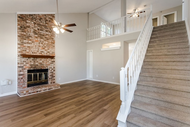 unfurnished living room featuring a fireplace, wood-type flooring, high vaulted ceiling, and ceiling fan