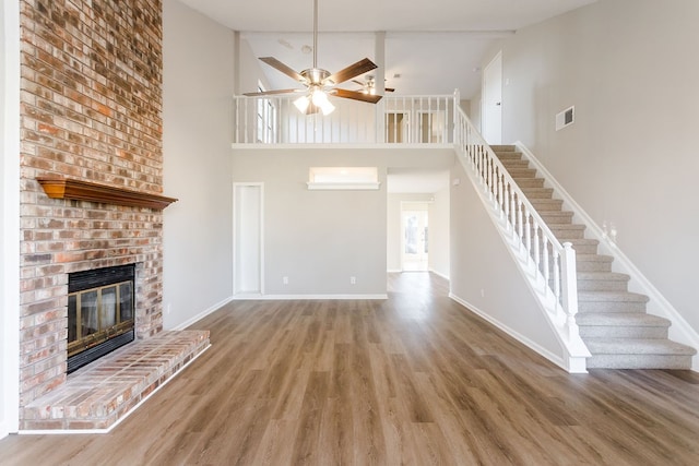 unfurnished living room with wood-type flooring, high vaulted ceiling, ceiling fan, and a brick fireplace