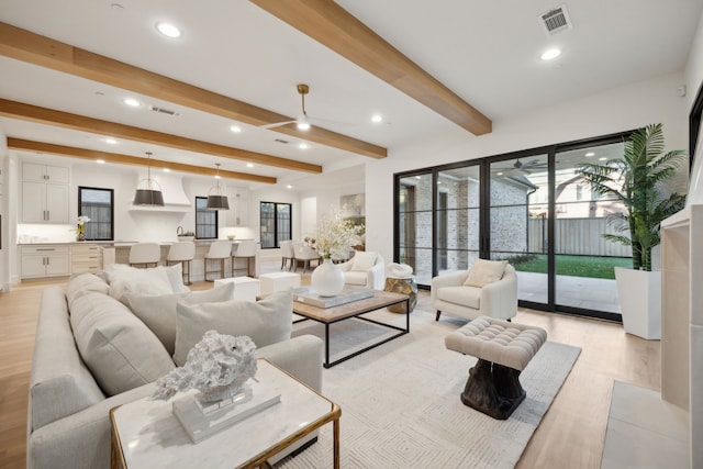 living room featuring ceiling fan, beamed ceiling, and light hardwood / wood-style floors