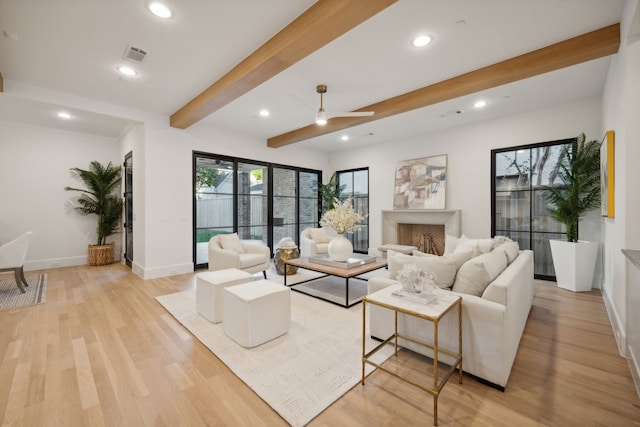 living room featuring beamed ceiling, light hardwood / wood-style floors, and ceiling fan