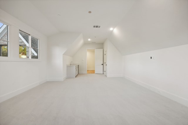 additional living space featuring sink, light colored carpet, and lofted ceiling