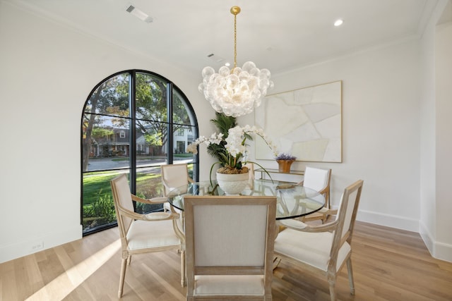 dining space featuring light hardwood / wood-style floors, crown molding, and a chandelier