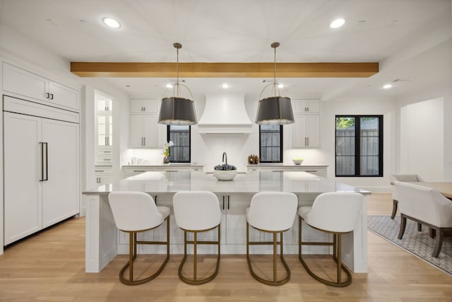 kitchen featuring paneled built in fridge, pendant lighting, white cabinets, and a spacious island