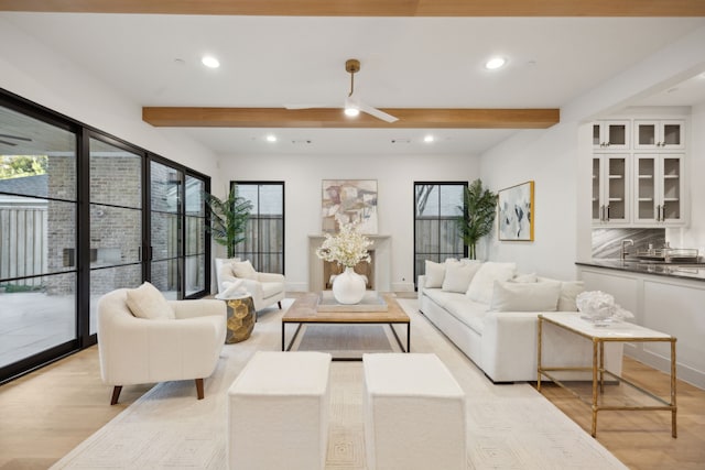 living room featuring beamed ceiling, light hardwood / wood-style floors, and ceiling fan