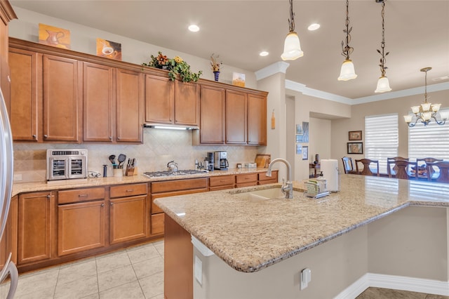 kitchen with an inviting chandelier, sink, ornamental molding, appliances with stainless steel finishes, and decorative light fixtures