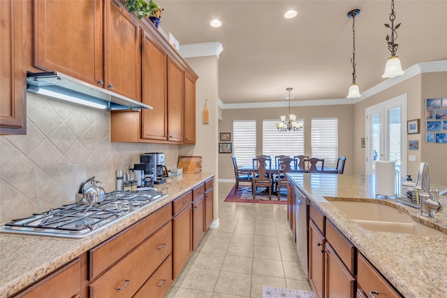 kitchen with appliances with stainless steel finishes, tasteful backsplash, decorative light fixtures, a kitchen island, and light stone counters