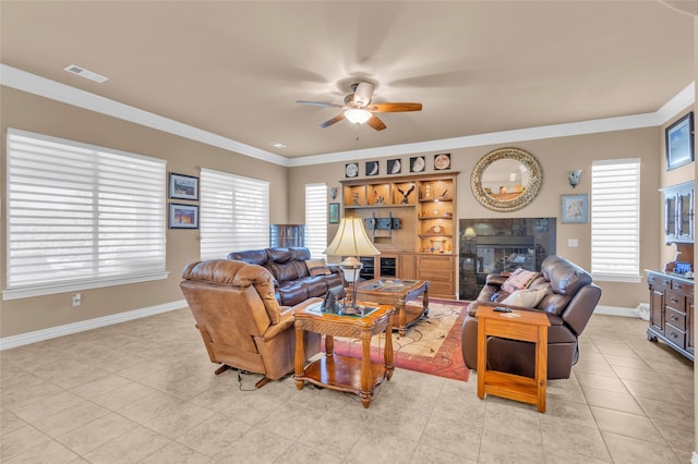 tiled living room featuring ceiling fan with notable chandelier, ornamental molding, and a wealth of natural light