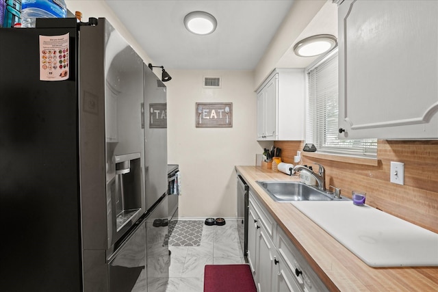 kitchen featuring white cabinets, butcher block countertops, stainless steel fridge with ice dispenser, and sink