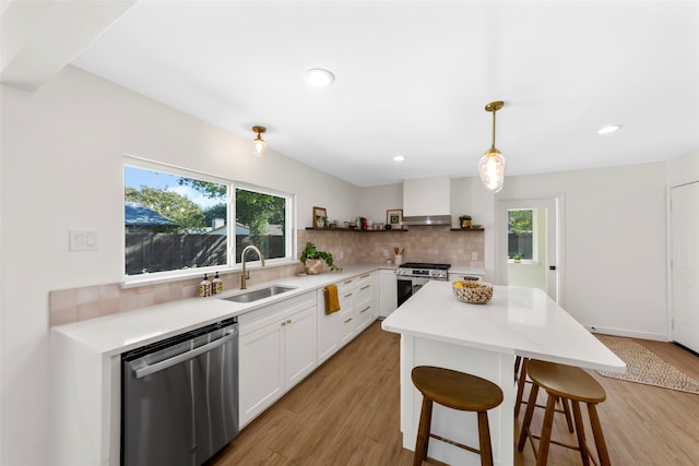 kitchen with white cabinetry, sink, hanging light fixtures, stainless steel appliances, and light wood-type flooring