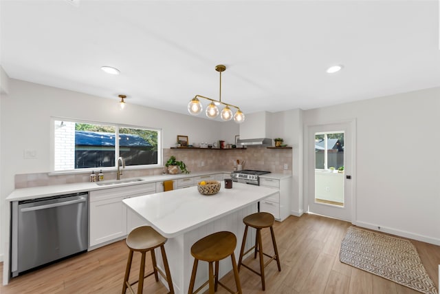 kitchen featuring white cabinetry, sink, stainless steel appliances, light hardwood / wood-style floors, and decorative light fixtures