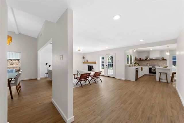 interior space featuring white cabinets, hanging light fixtures, a brick fireplace, light hardwood / wood-style floors, and stainless steel appliances