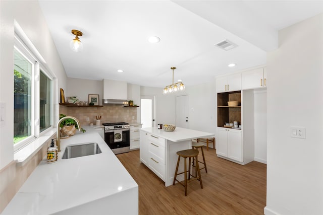 kitchen featuring white cabinetry, stainless steel range with gas cooktop, sink, and pendant lighting