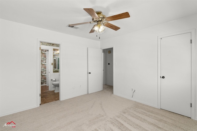 unfurnished bedroom with ceiling fan, ensuite bathroom, and light colored carpet