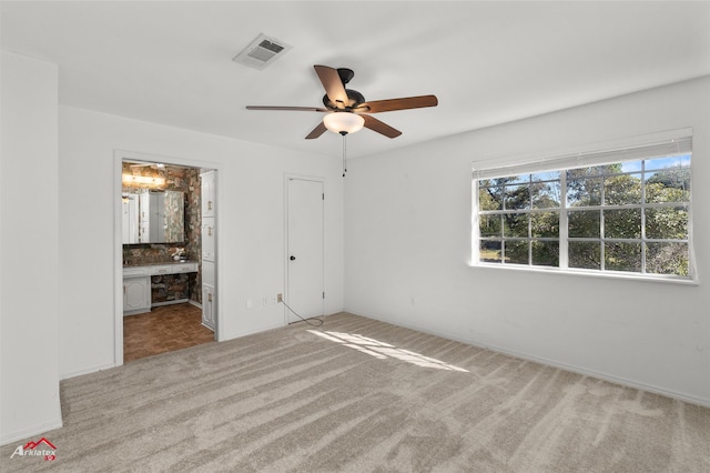 unfurnished bedroom with ensuite bathroom, ceiling fan, and light colored carpet