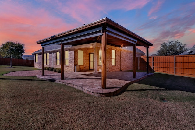 back house at dusk with a yard and a patio area