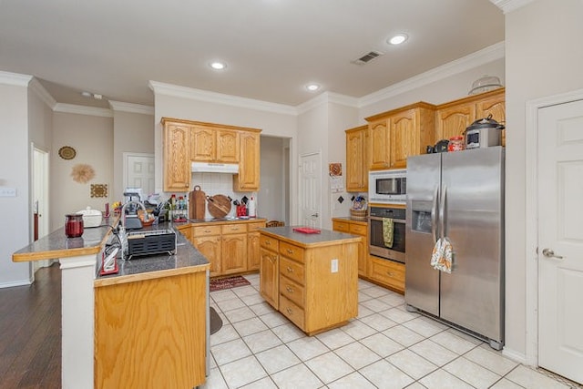 kitchen featuring appliances with stainless steel finishes, tasteful backsplash, ornamental molding, light hardwood / wood-style flooring, and a kitchen island