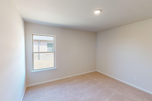 empty room featuring light carpet and baseboards