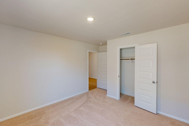 unfurnished bedroom with light colored carpet, a closet, visible vents, and baseboards