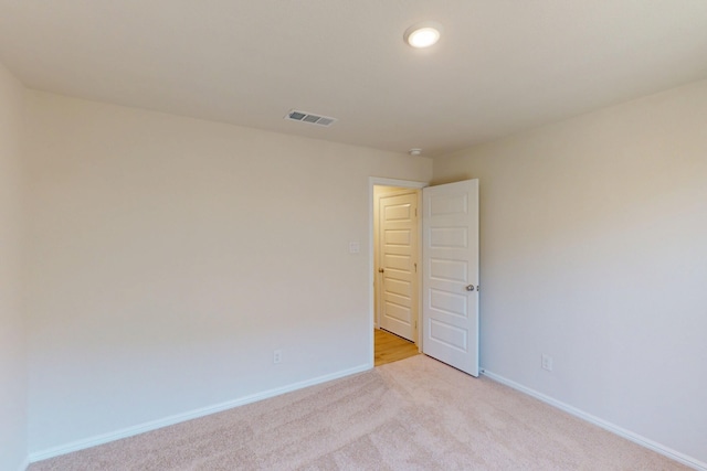 empty room featuring light carpet, baseboards, and visible vents