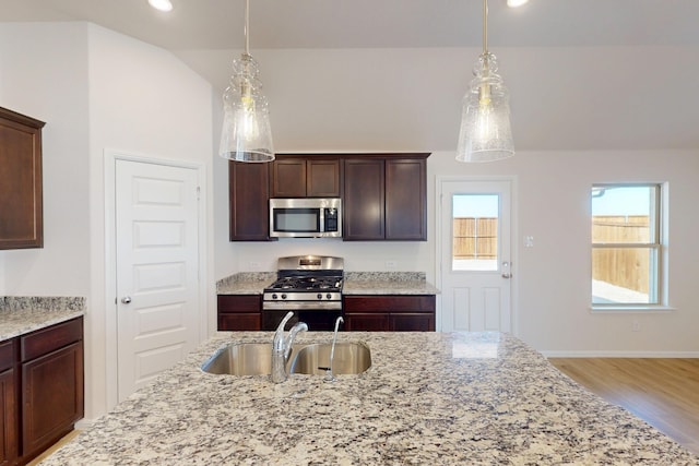 kitchen featuring appliances with stainless steel finishes, pendant lighting, a sink, and dark brown cabinets