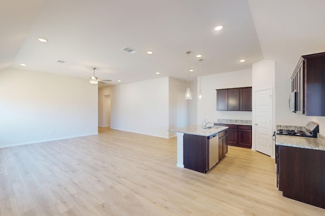 kitchen with decorative light fixtures, a center island with sink, visible vents, light wood-style flooring, and open floor plan