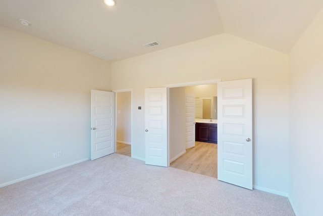 unfurnished bedroom with vaulted ceiling, light carpet, visible vents, and baseboards