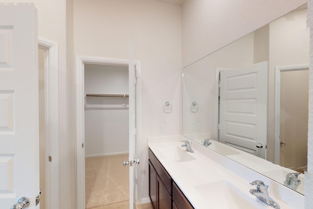 full bathroom with a spacious closet, double vanity, and a sink