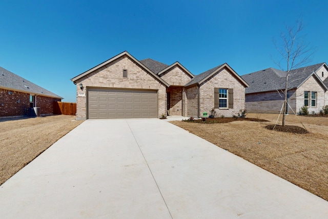 view of front facade featuring brick siding, driveway, an attached garage, and fence