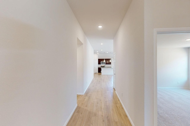 corridor featuring light wood-style floors, recessed lighting, and baseboards