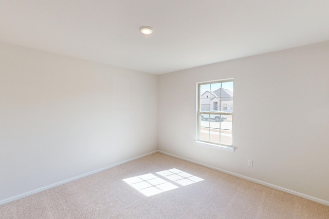 unfurnished room featuring light colored carpet and baseboards