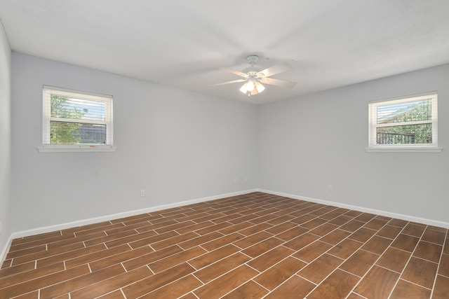 unfurnished room featuring a wealth of natural light, ceiling fan, and dark wood-type flooring